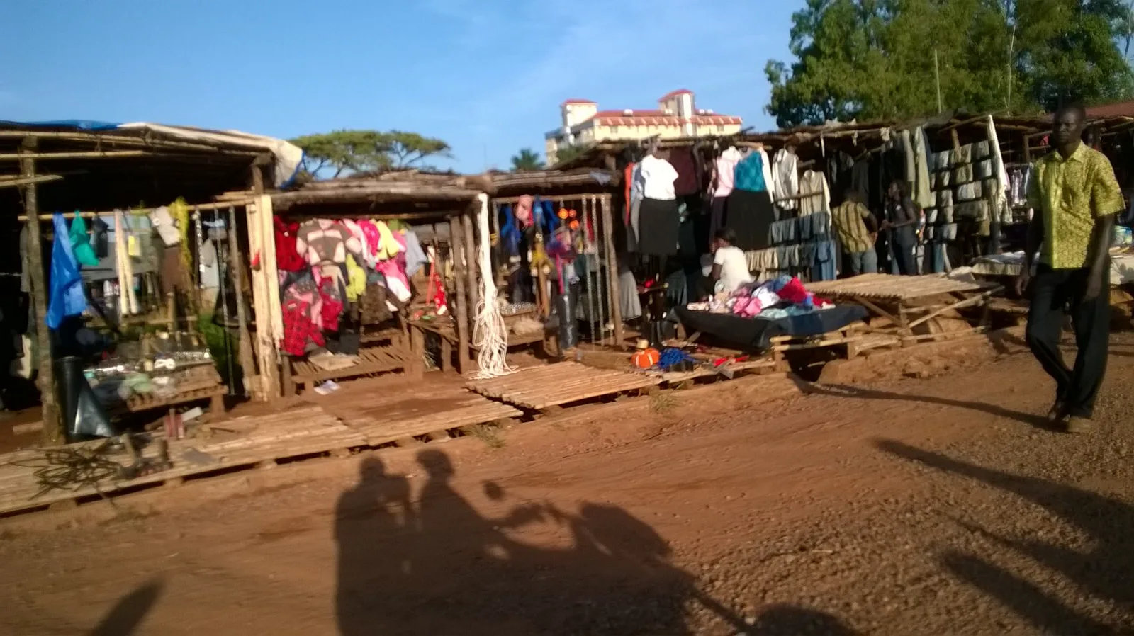 Clothing stalls along a dirt road through the market.