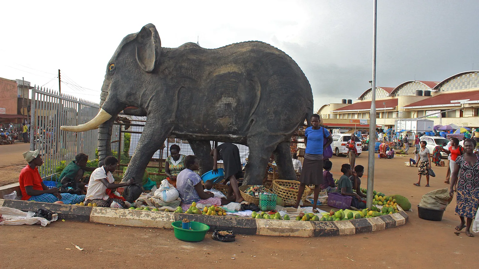 Produce sellers working under the statue at the market gate.